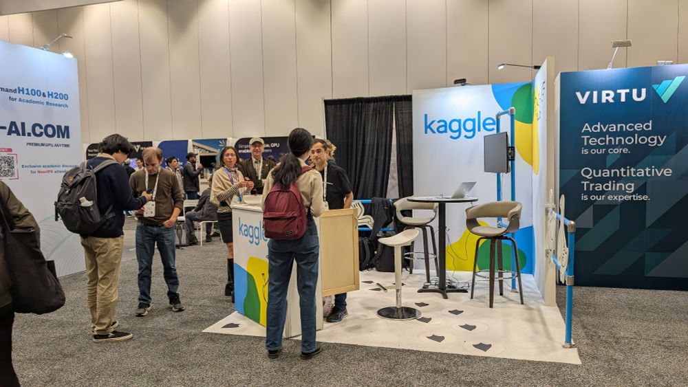 A group of people talking in front of the Kaggle booth.