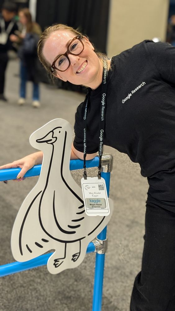 Meg smiling brightly while leaning over a cheerful line drawing of a goose on a cutout.