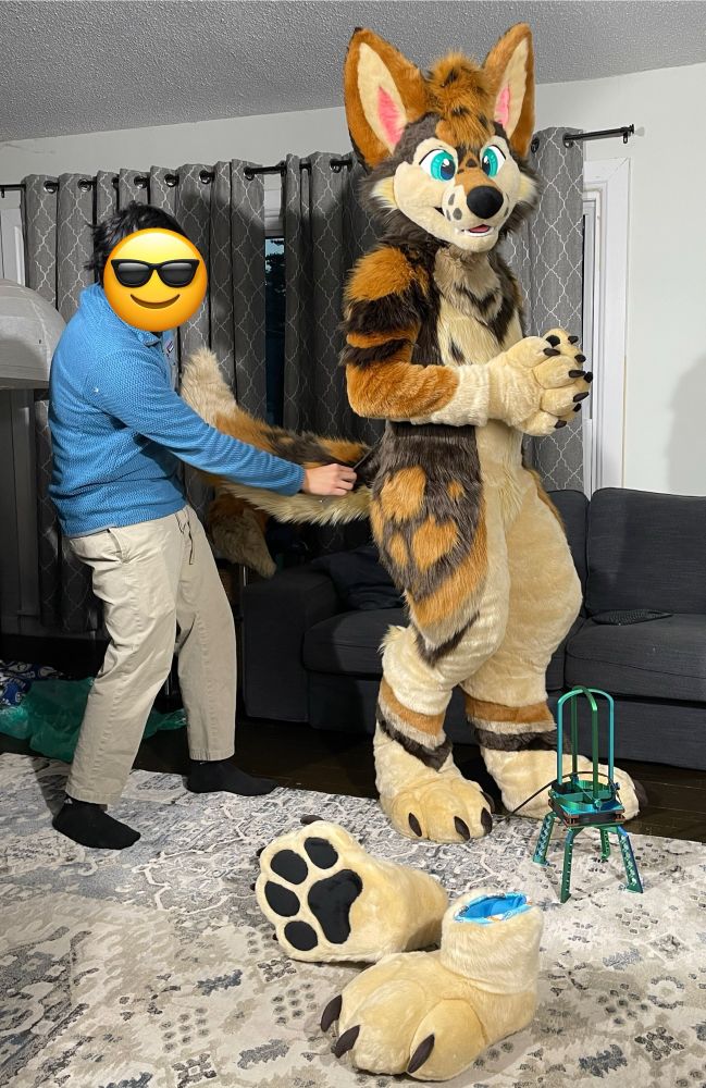 A fursuiter gets his tail combed out for the camera 