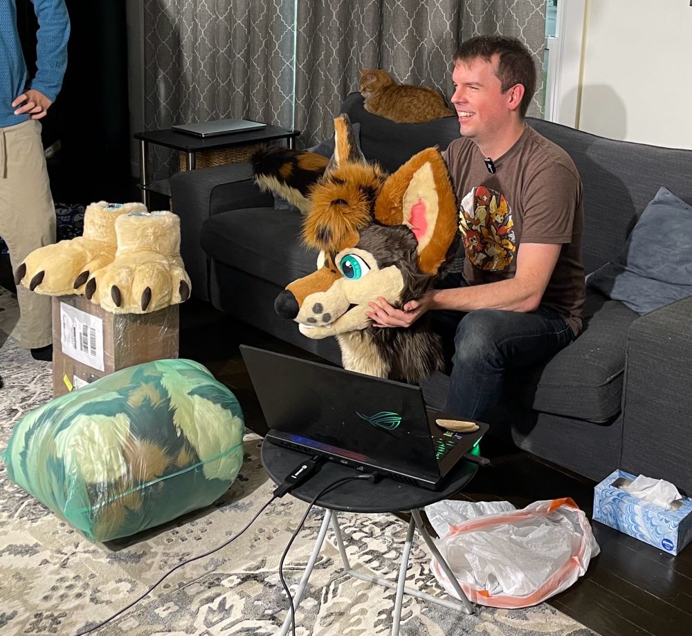 Some guy holds up a fursuit head fresh from the packaging 