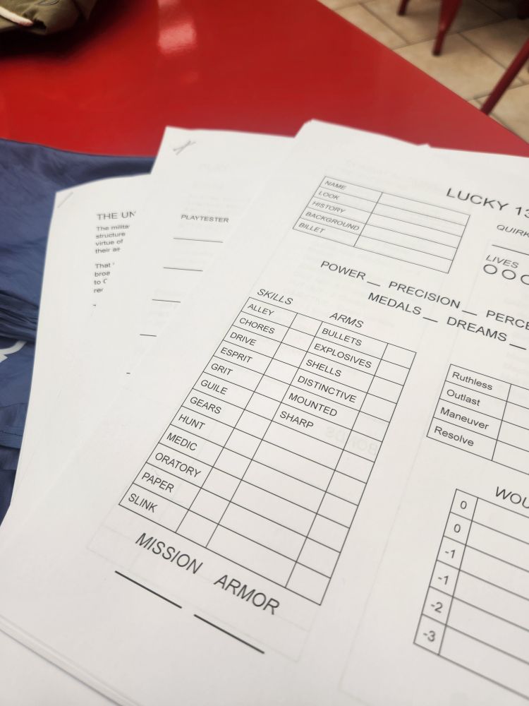 Playtest materials for Lucky 13, splayed out so that multiple pages are visible