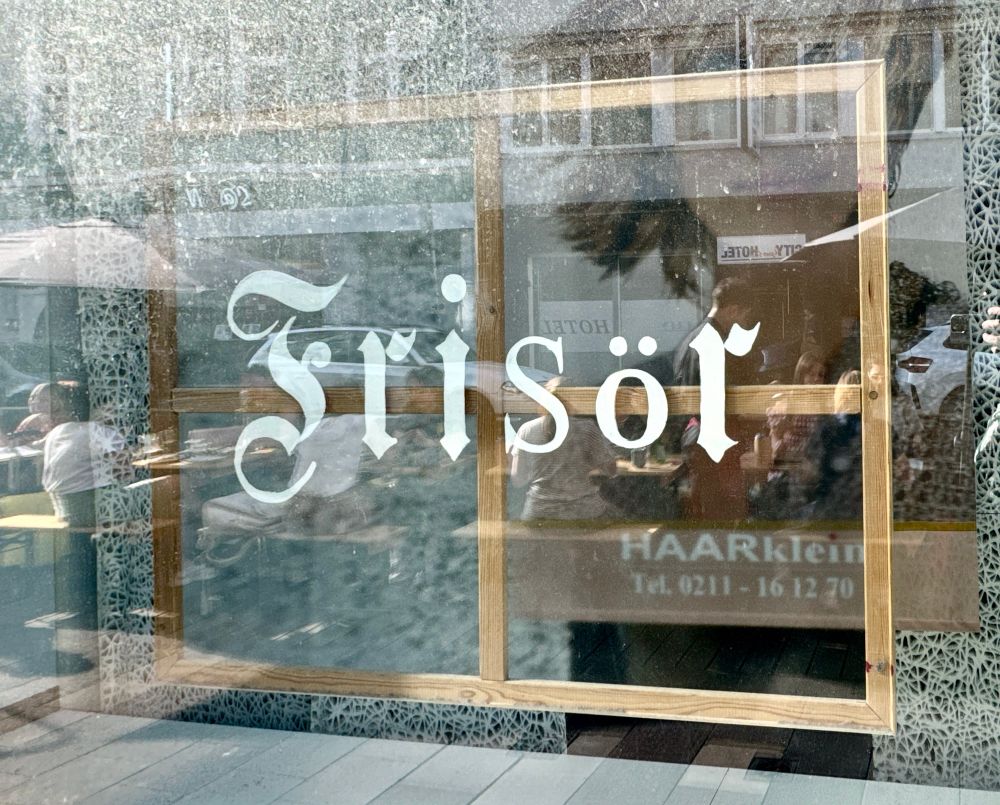 Schild „Frisör“ in eonem Schaufenster. Die Buchstaben F, R, I und R sind in der Titelschrift der FAZ gesetzt, S und Ö aus zwei anderen Serifenfonts.