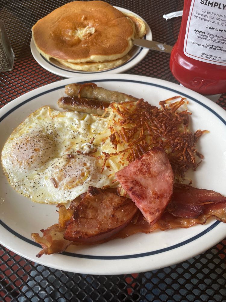 A plate of breakfast food with two very small pieces of ham.