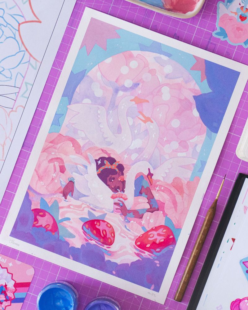 A pciture of a painting surrounded by the materials used to paint them. The painting is an illustration picturing awoman laying her head on a swan's back. The woman is black skinned, whe is wearing an orange polkadot bandana and colorful starry tattoos. She is sipping a pink drink with a straw from petal ornemented cup. She's surrounded and half covered by giant peonies. Three shiny strawberries are floating in water the foreground. In the pastel background we can see two other swans and giant peonies. The scene is framed by a starry arch.