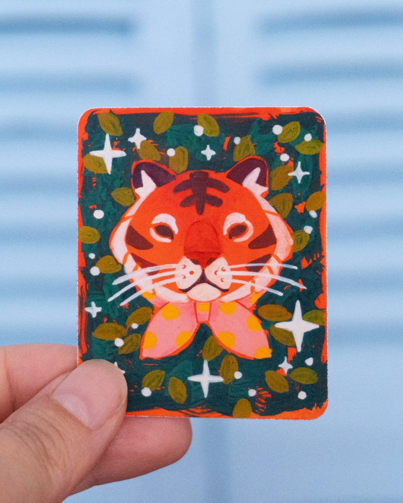 a vibrant expressive painting of a tiger wearing a pink polkadot bow on a dark green background - made into a sticker
