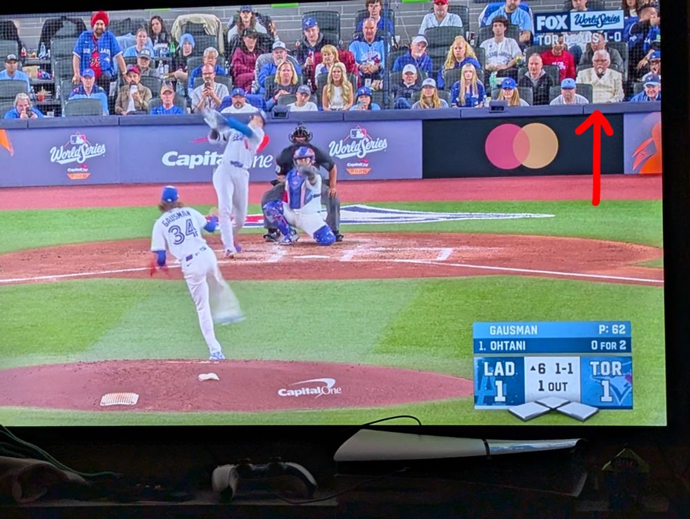 jays vs dodgers top of the 6th. an arrow is pointing to a fan in the background with white hair and a goatee, wearing a white suit