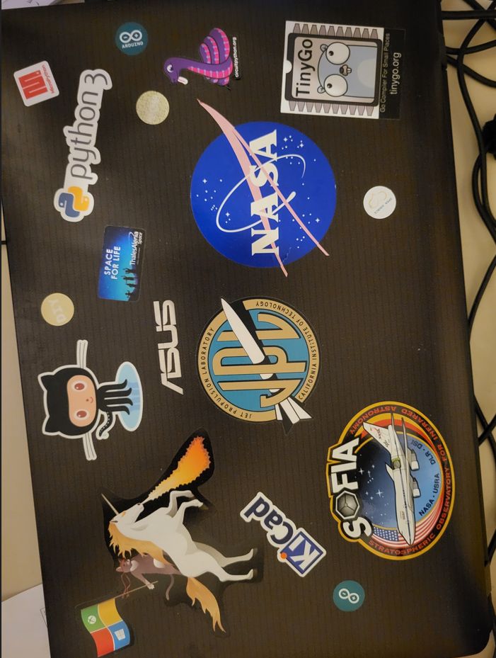 An old ASUS  19" laptop with lots of stickers (NASA, JPL, Windows Unicorn, Python 3, TinyGo, KiCAD, Arduino,...)