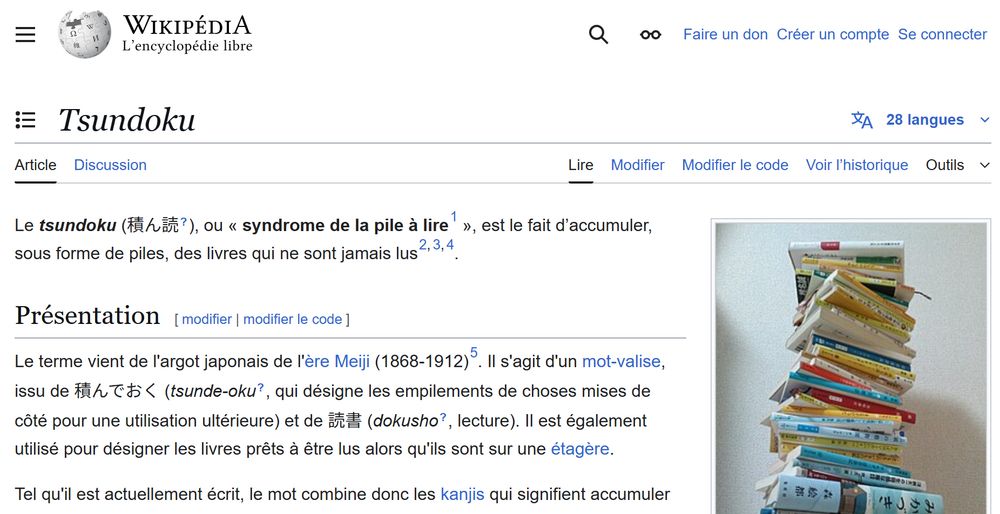 Extrait de la page Wikipedia de 積ん読 avec une photo d'une pile de livres