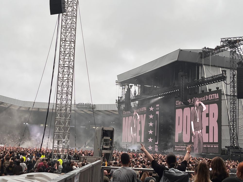 A picture of Kendrick Lamar in front of Money and Power backdrop