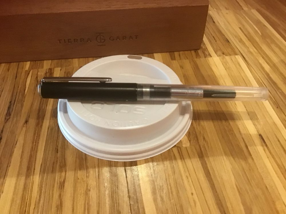 Sailor Compass fountain pen in clear plastic and a black cap with aluminum clip. You can see the converter with blue Parker Qink.