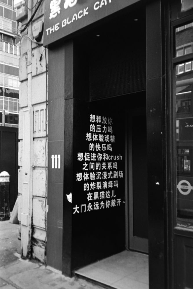 entrance to place on fleet street, "the black ca[t club]"

writing in chinese on wall next to door. number 111