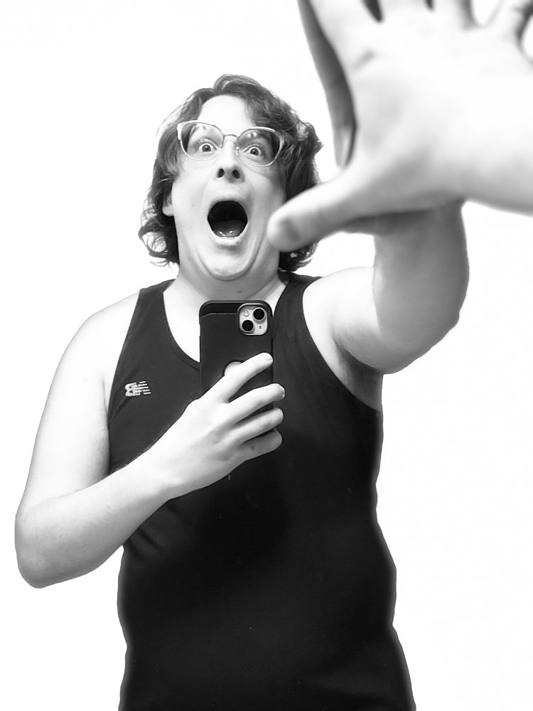 black and white photo with pure white background, a nonbinary person with short wavy hair and glasses in a tank too screams in a mirror, hand touching glass