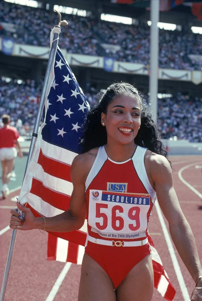 SEOUL, SOUTH KOREA – SEPTEMBER 28: Florence Griffith Joyner of the USA walks with the American Flag as she celebrates setting a new Olympic record to win the gold medal in the Women’s 100 meters dash final during the 1988 Summer Olympic Games on September 28, 1988 in Seoul, Korea. (Photo by Tony Duffy/Getty Images) 