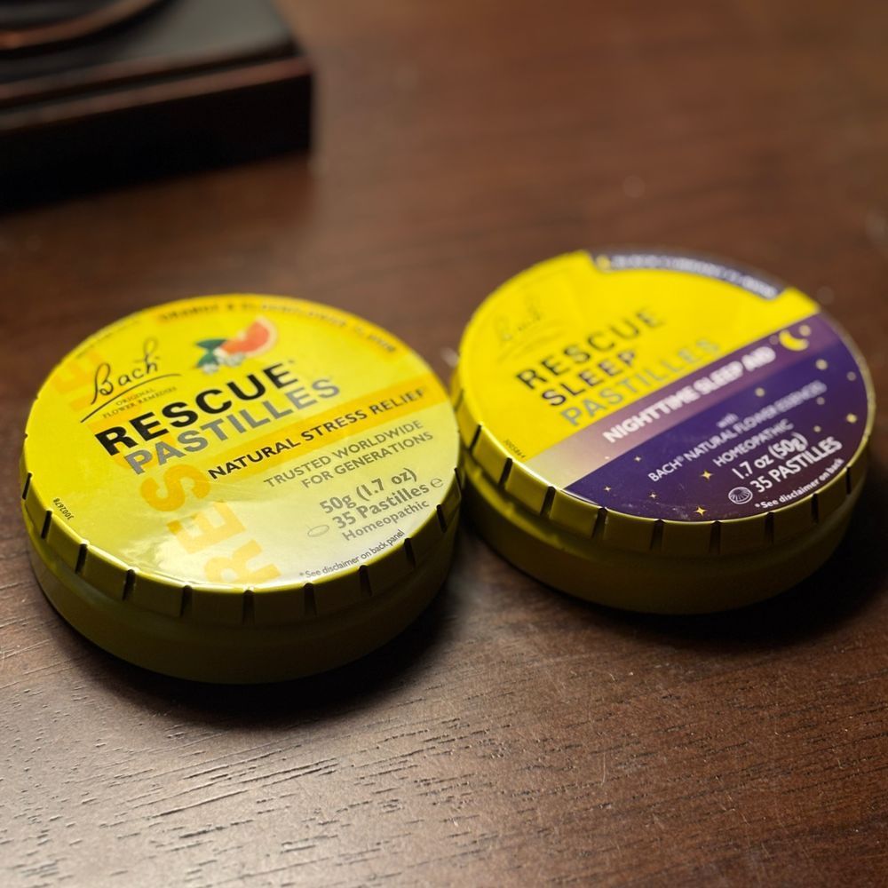 Two tins of pastilles on a wood table. 