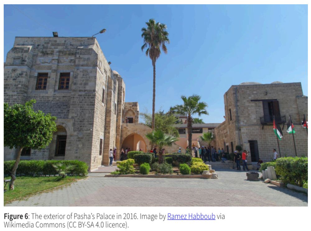 The exterior of Pasha's Palace in 2016: photo of an intact building with palm trees and other landscaping on a sunny day