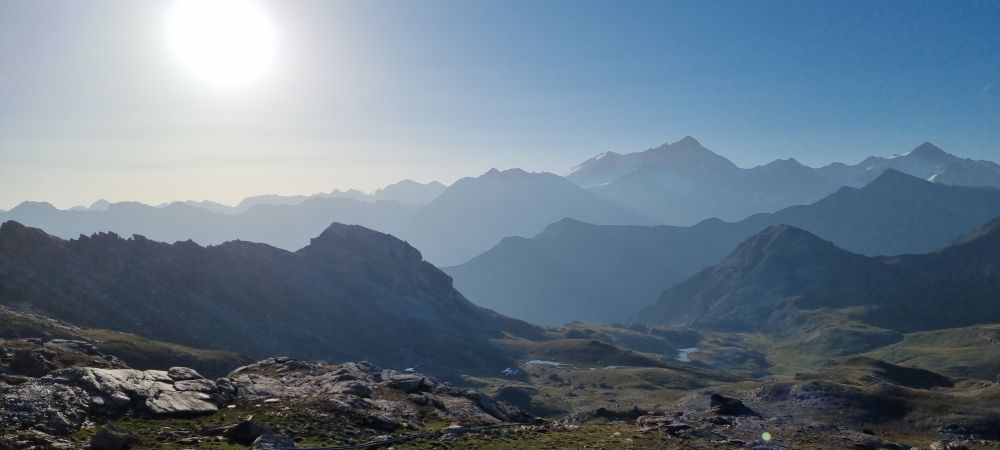 Morning light over an alpine landscape with many summits visible. The low angle sunlight produces many different grey shades at the horizon. The photo was taken from the cabane de becs de Bosson, 2985 m