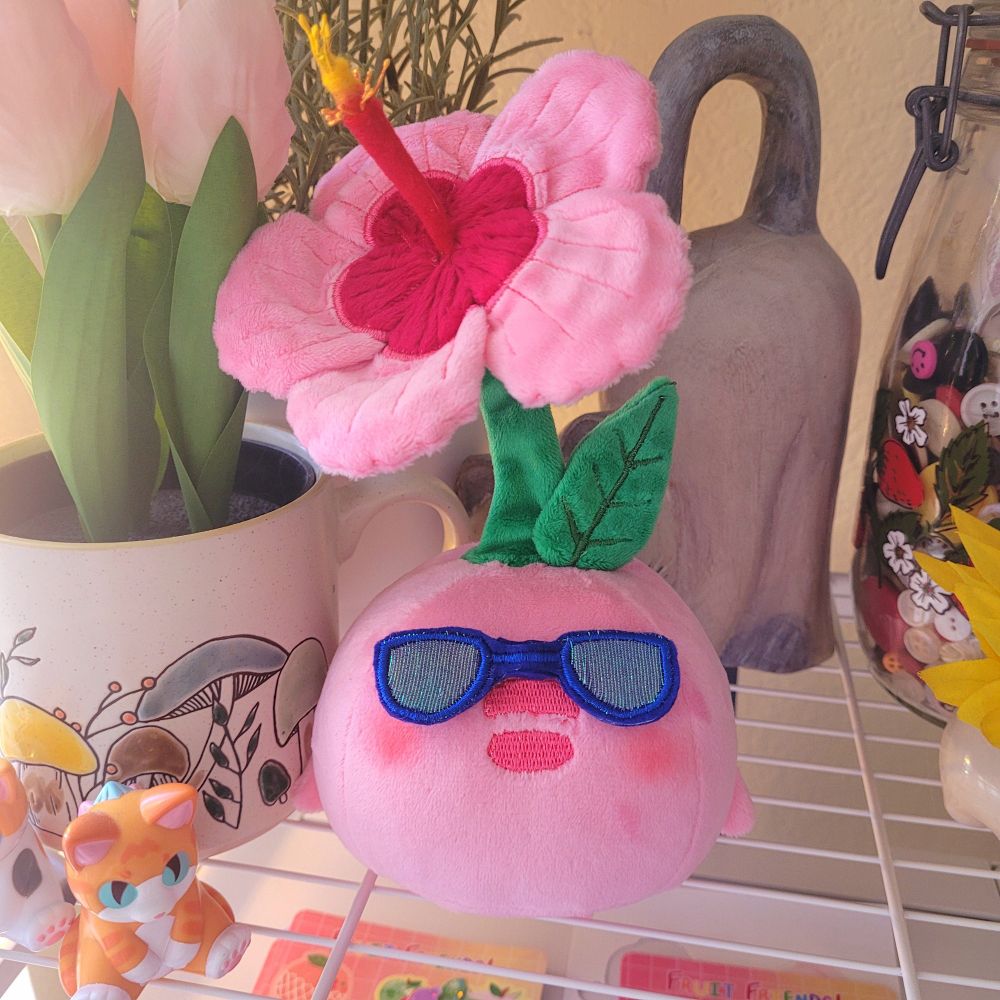 A picture of the same plush from the previous image. It has blue sunglasses on, which are held in place with hidden magnets.