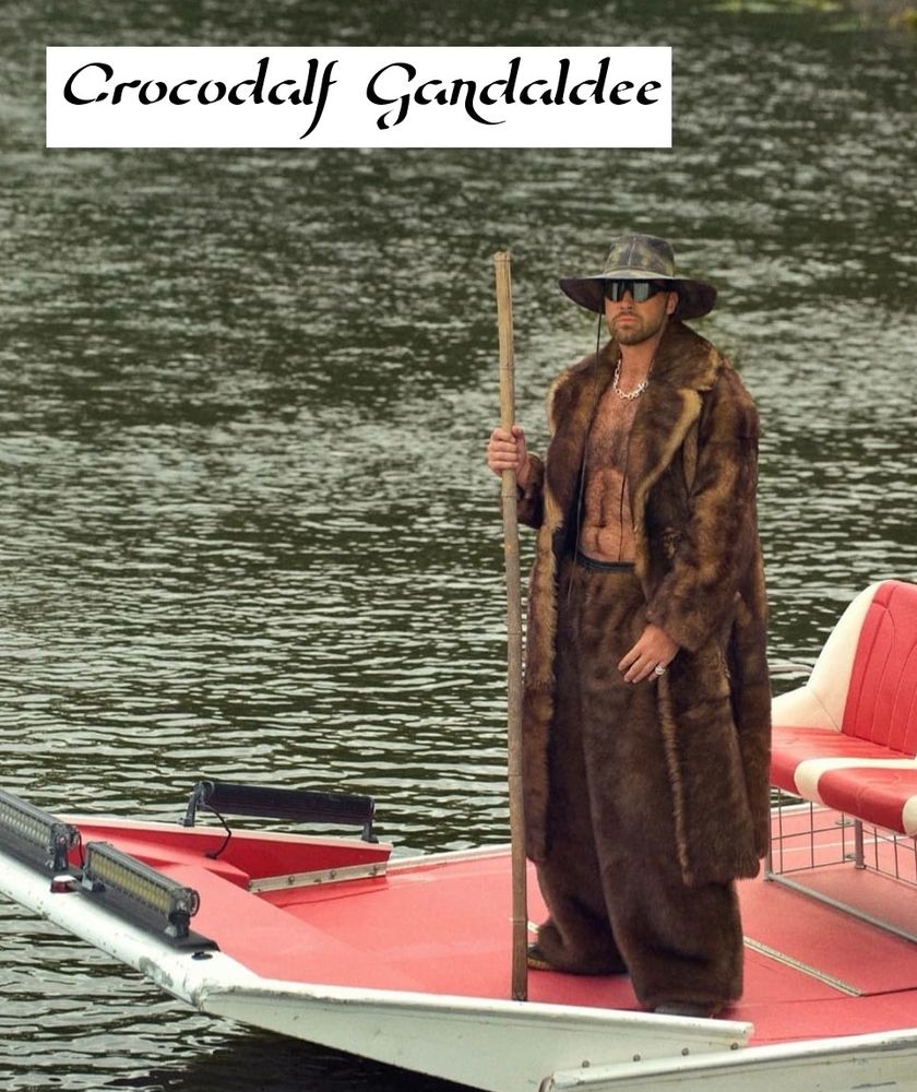 Man wearing a robe, a hat and a staff on a boat. Looking like a crossover of Gandalf and Crocodile Dundee