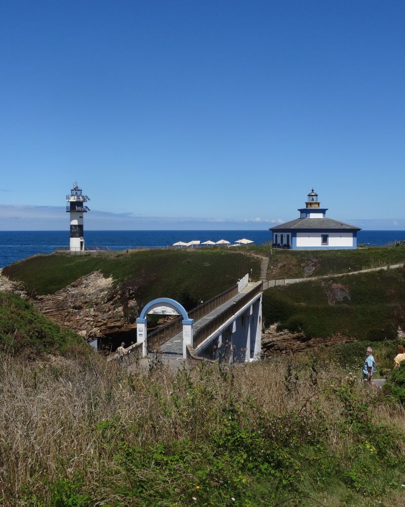 Faro en el lado izquierdo, casa del faro en el lado derecho y puente que cruza desde la orilla en la que se toma la foto hasta la isla en la que están el faro y la casa del faro 
