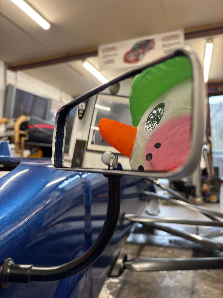 Picture of a race car mirror with an inflatable snowman in the mirror