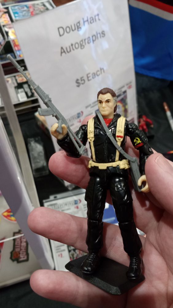 A photo of Volk, a vintage O-ring style action figure of an aged soviet soldier in a black uniform with tan web gear brandishing an AK74, held in my hand