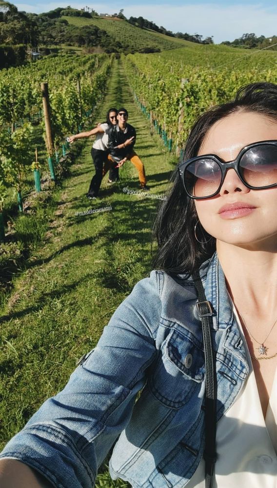 A selfie of ruibo with madeleine and vico in the back on a field from ofmd season 2 filming times