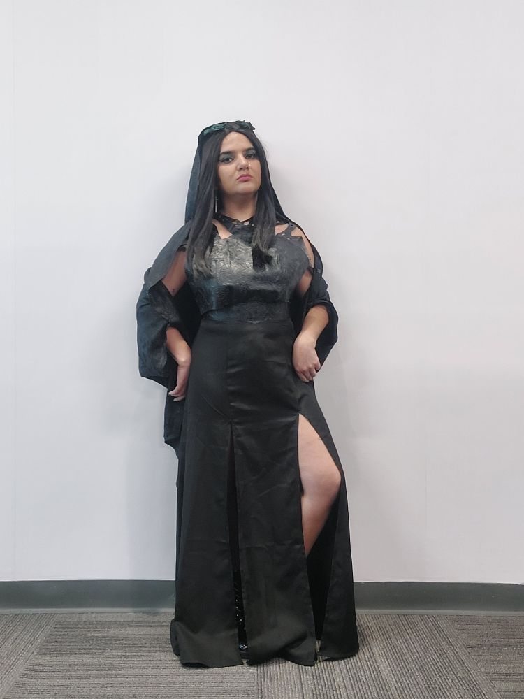 A full body picture of ally standing in front of a white wall dressed up as rio vidal