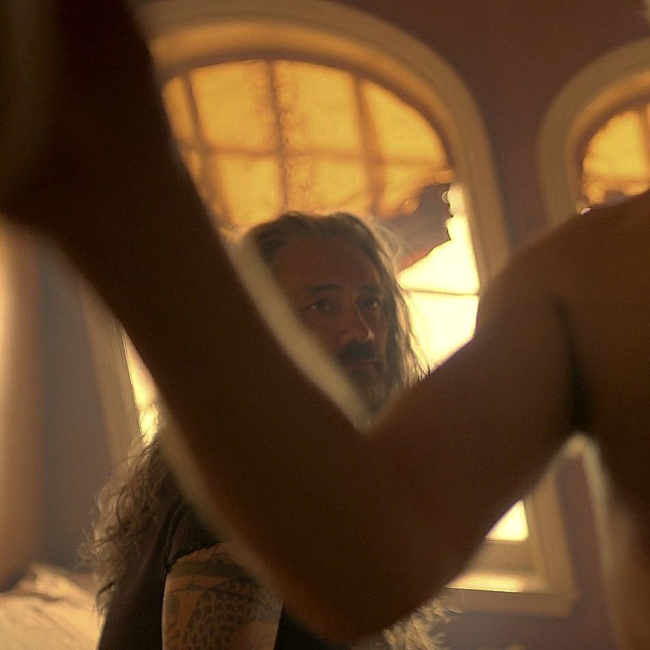 A picture from ofmd season 2 episode 6 of ed sitting on the bed nook looking at shirtless stede as he closes the curtain before they have sex