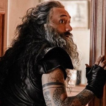 A picture from ofmd season 1 of ed from the back, looking to the side with his hand on the door frame