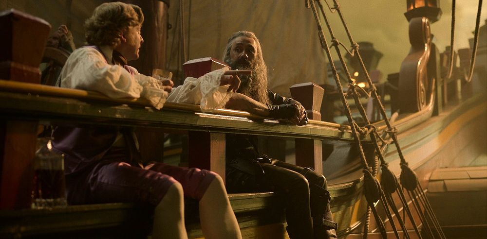 A picture from ofmd season 1 of stede and ed sitting with their feet hanging on the side of the ship 