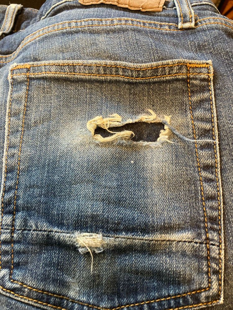 Back pocket of jeans with a hole in them. 