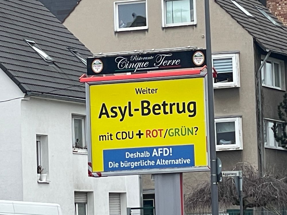 Ein Wahlplakat. Gelber Hintergrund. Darauf der Text: Weiter Asylbetrug mit CDU+ROT/GRÜN? Deshalb AFD! Die bürgerliche Alternative. Das Plakat ist nicht in den offiziellen AfD-Farben und auch das Logo fehlt. 