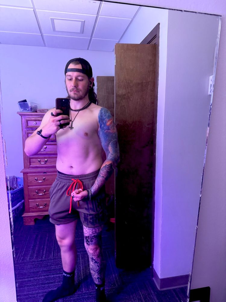 Shirtless tattooed man flexes in mirror