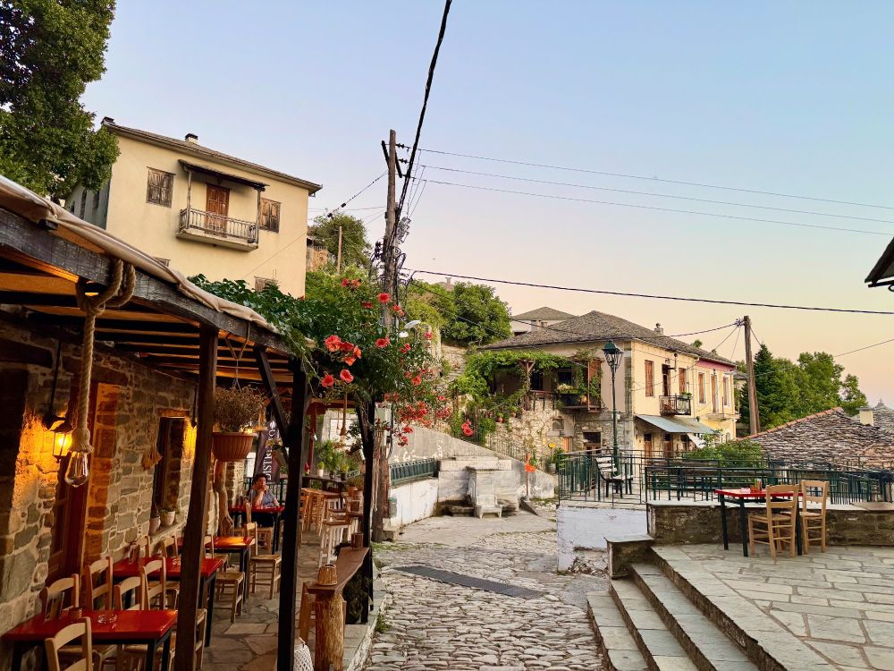 A stone paved street outside a taverna at sunset
