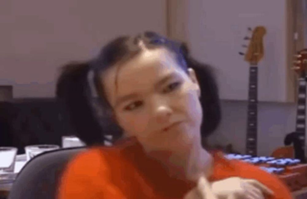 a woman in a red shirt is sitting in front of a guitar .