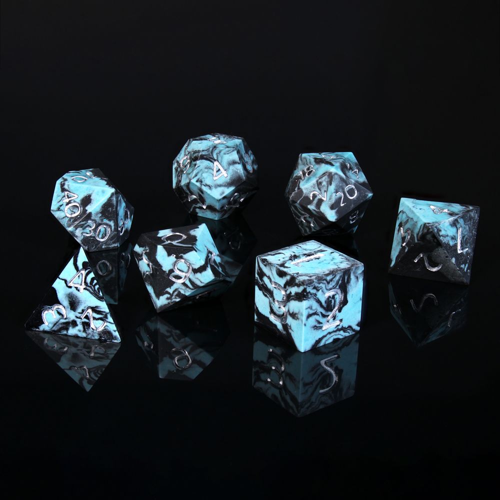 A set of 7 polyhedral dice. They are a marble like effect in a light blue and black. The numbers are painted silver.