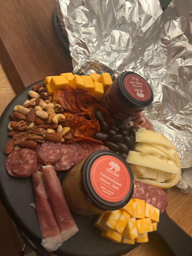 a picture of my charcuterie board, filled with gouda, colby, and sharp cheddar cheese, soppressata, prosciutto and chorizo, different nuts and 2 jams. One is a caramelized onion jam and the other is peruvian pepper 