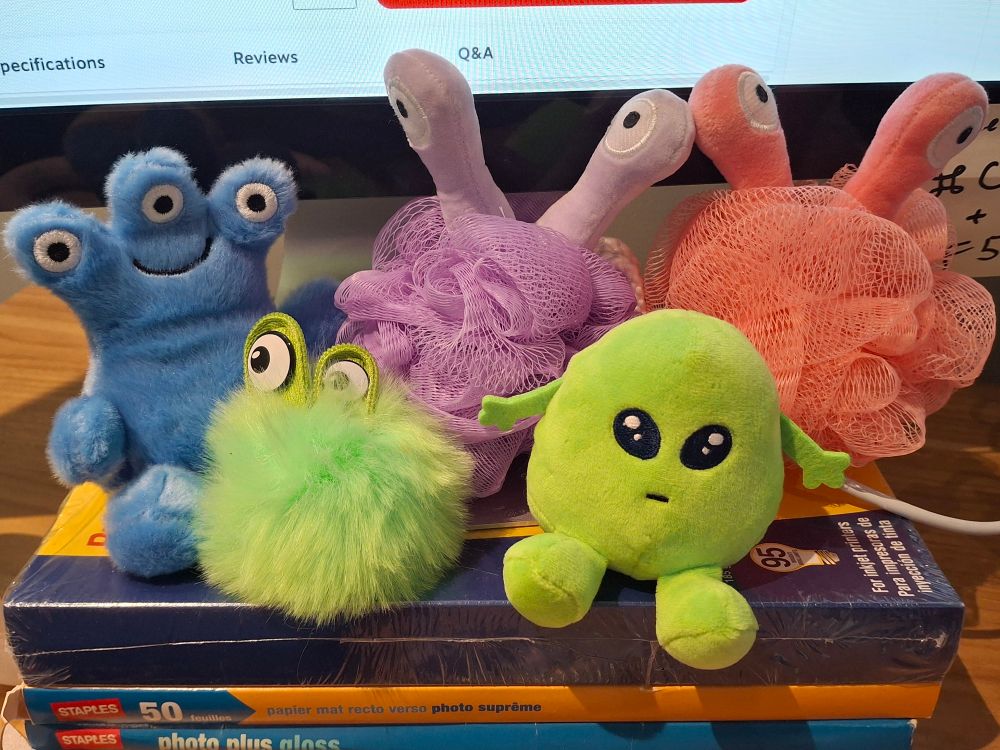 a collection of colorful alien plushies. they're all pretty round with various numbers of eye stalks.
