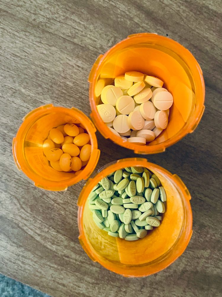 Pill bottles full of spironolactone (top), progesterone (middle), and estradiol (bottom)
