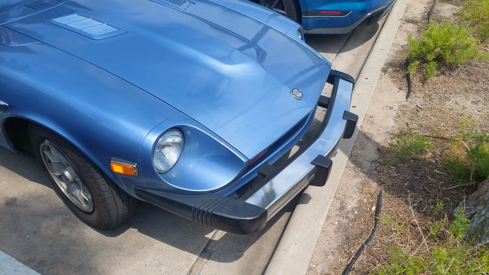 The front bumper of the Datsun 280Z with about 3 inches of open space between the bumper and the car.