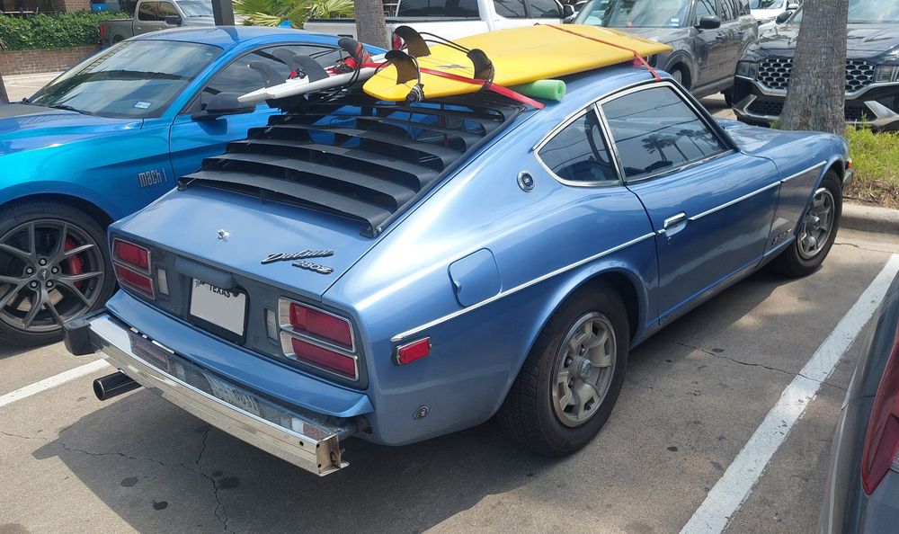 Right rear quarter panel shot of the sky blue 280Z with 2 surf boards strapped to the roof.