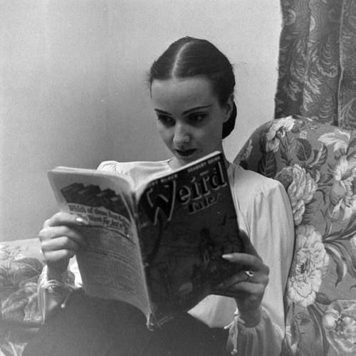 A photograph of a woman reading an issue of Weird Tales, taken by Allan Grant.