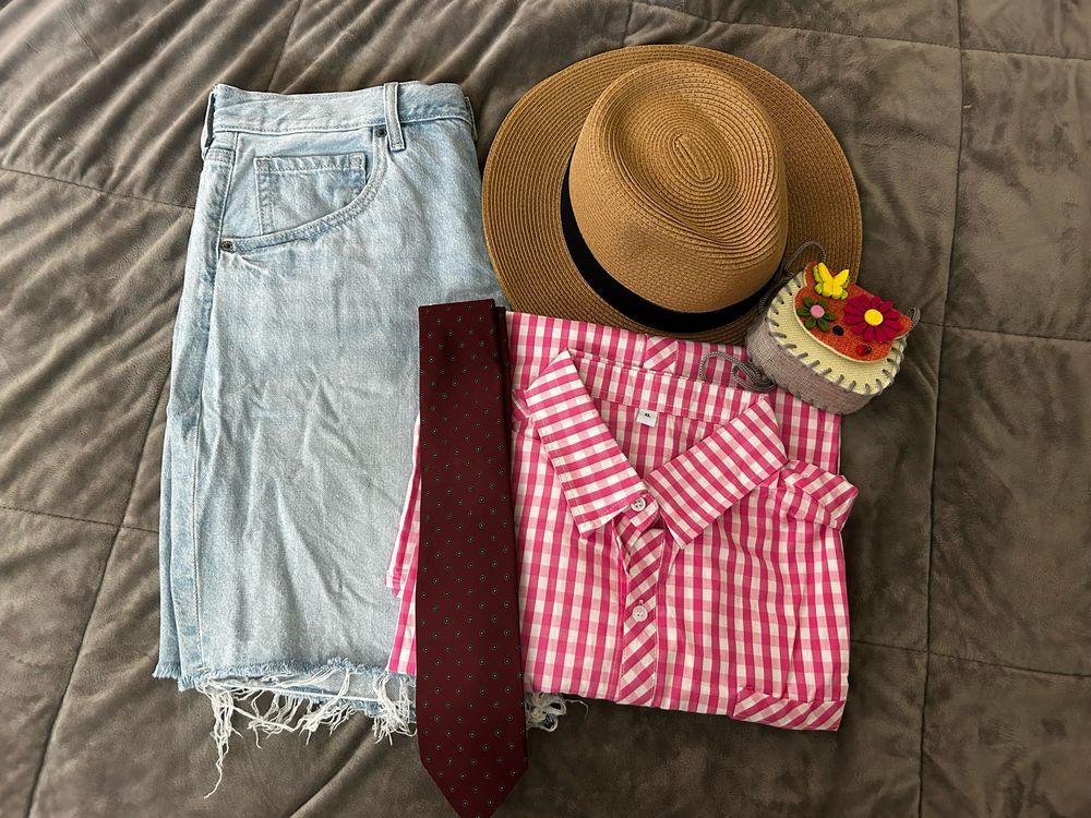 Flat lay of jeans shorts, pink gingham shirt, straw hat & tie to match BTS Jin in Malta 