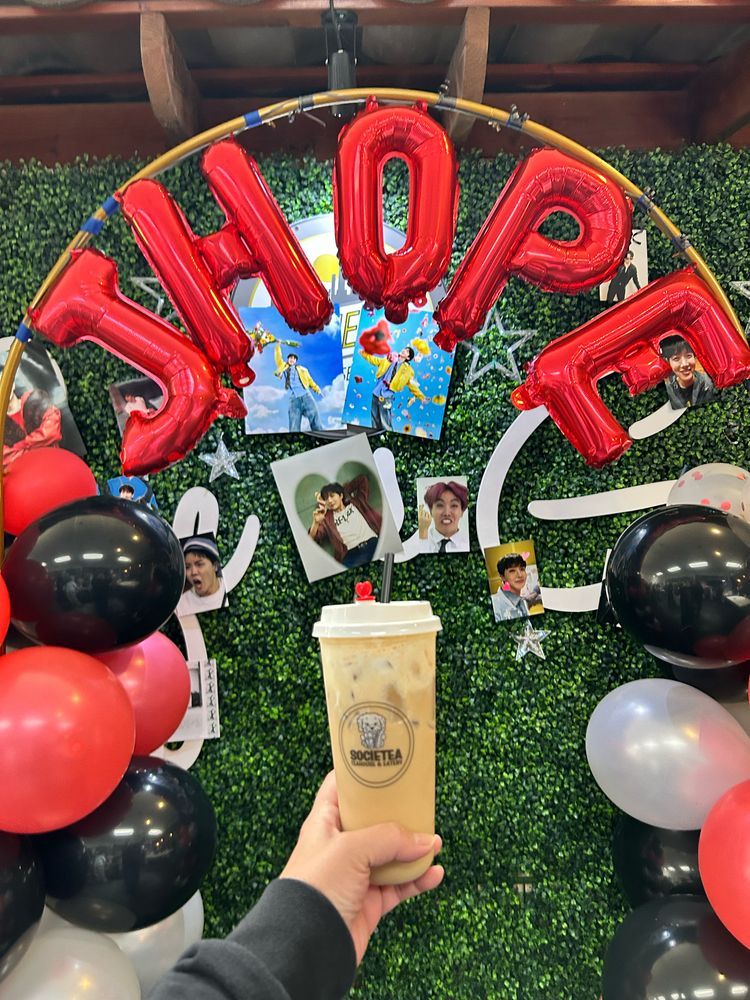 Bubble tea drink with balloon signs spelling JHope & photos of JHope on the wall. 