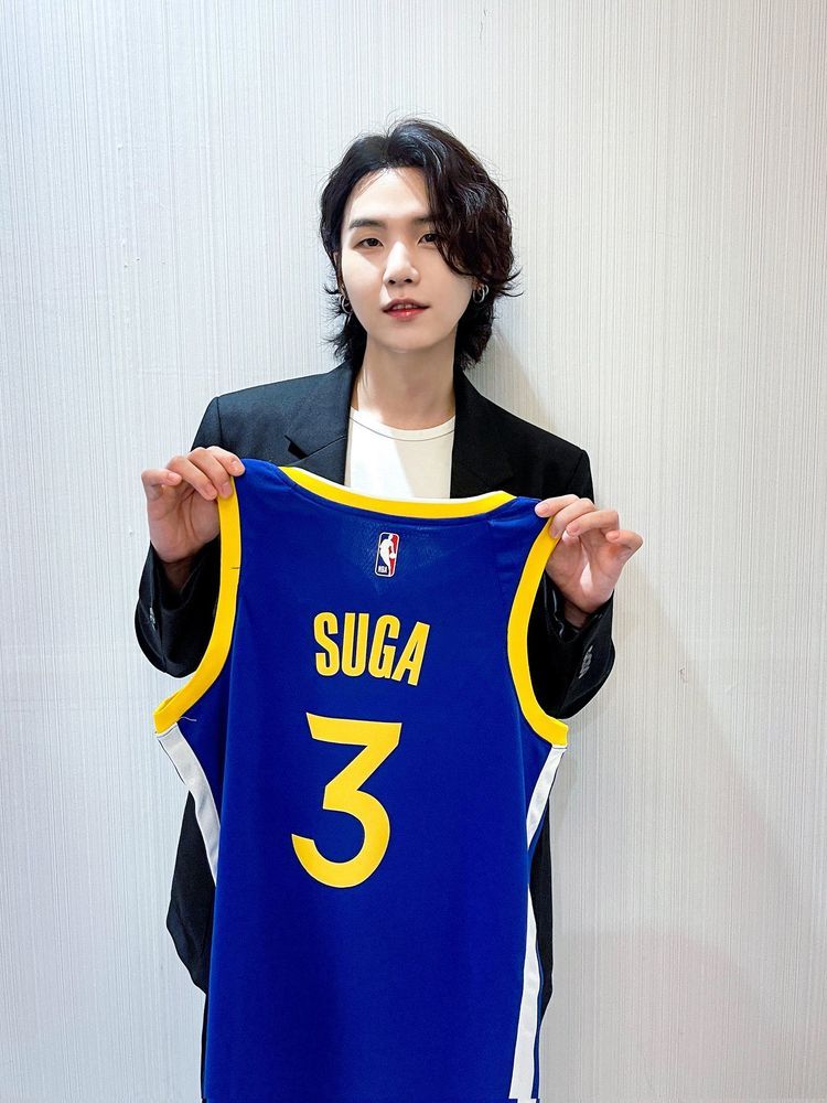BTS Suga holding his custom Golden State Warriors jersey with his name and number 3 