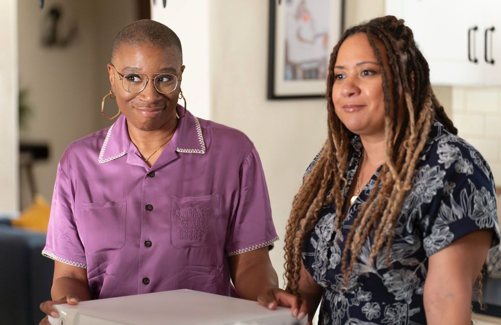 hen and karen both looking gorgeous and stylish standing in the kitchen with hen holding a cake box