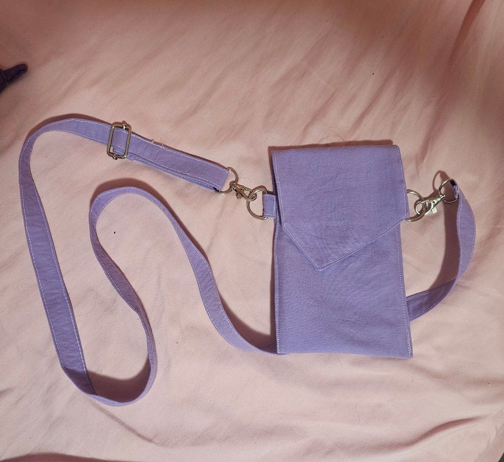 a purple bag roughly the size of a large smart phone with an adjustable strap