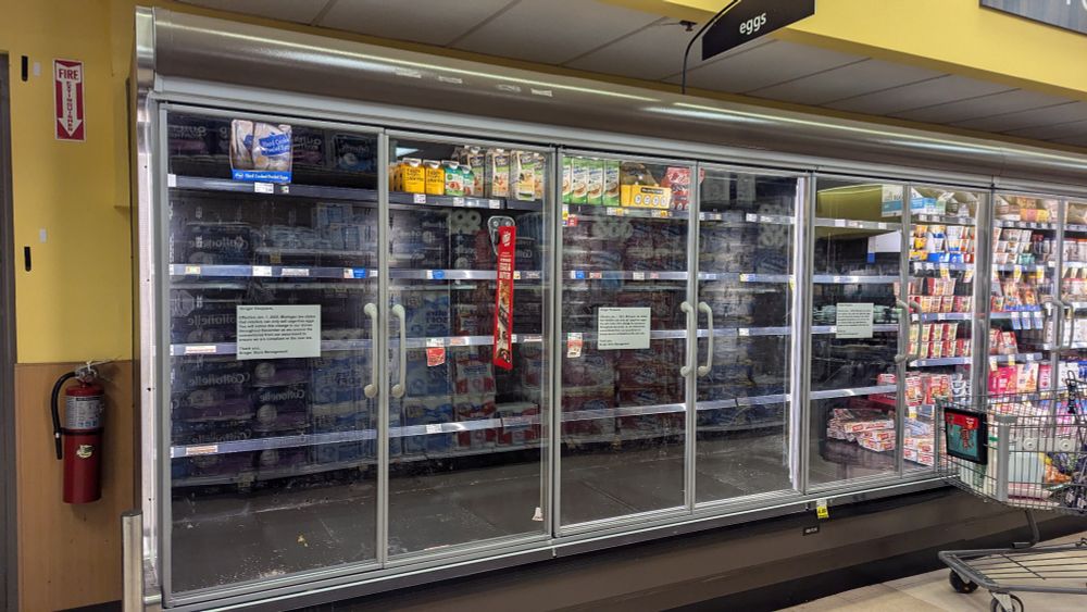 Picture of grocery store egg section completely empty without a single egg and 3 signs saying "Michigan law has taken effect and as of January 1st, stores are not allowed to sell non cage-free eggs.