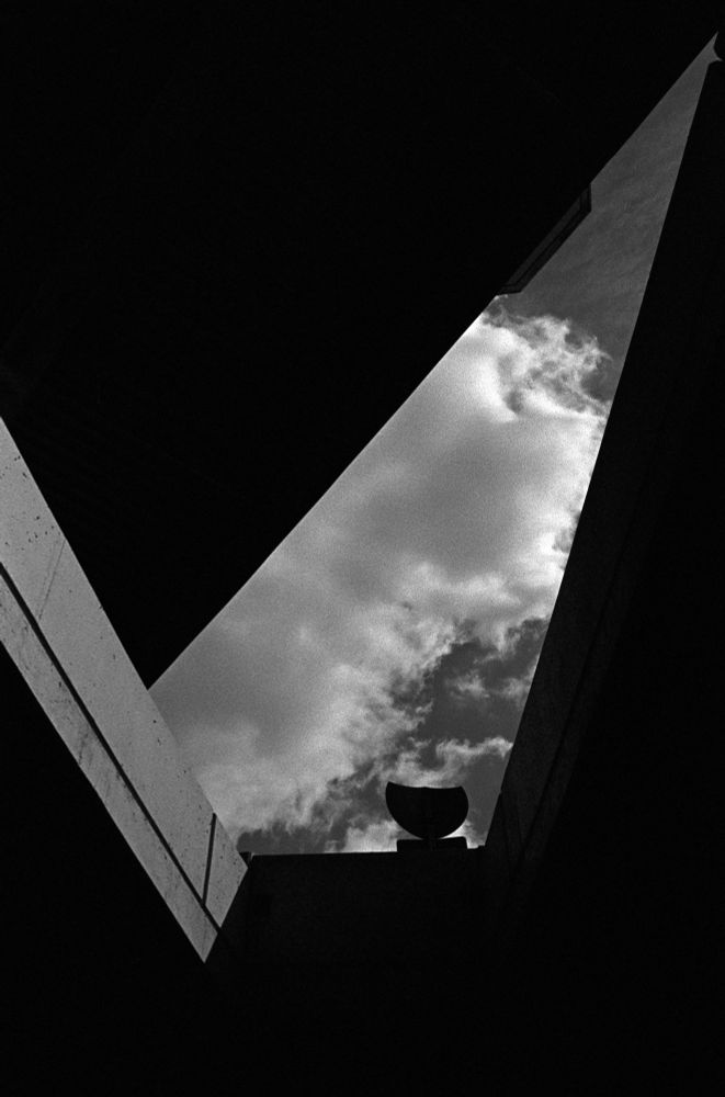 Black and white photo of an abstract looking triangle of sky taken from under a highway. 