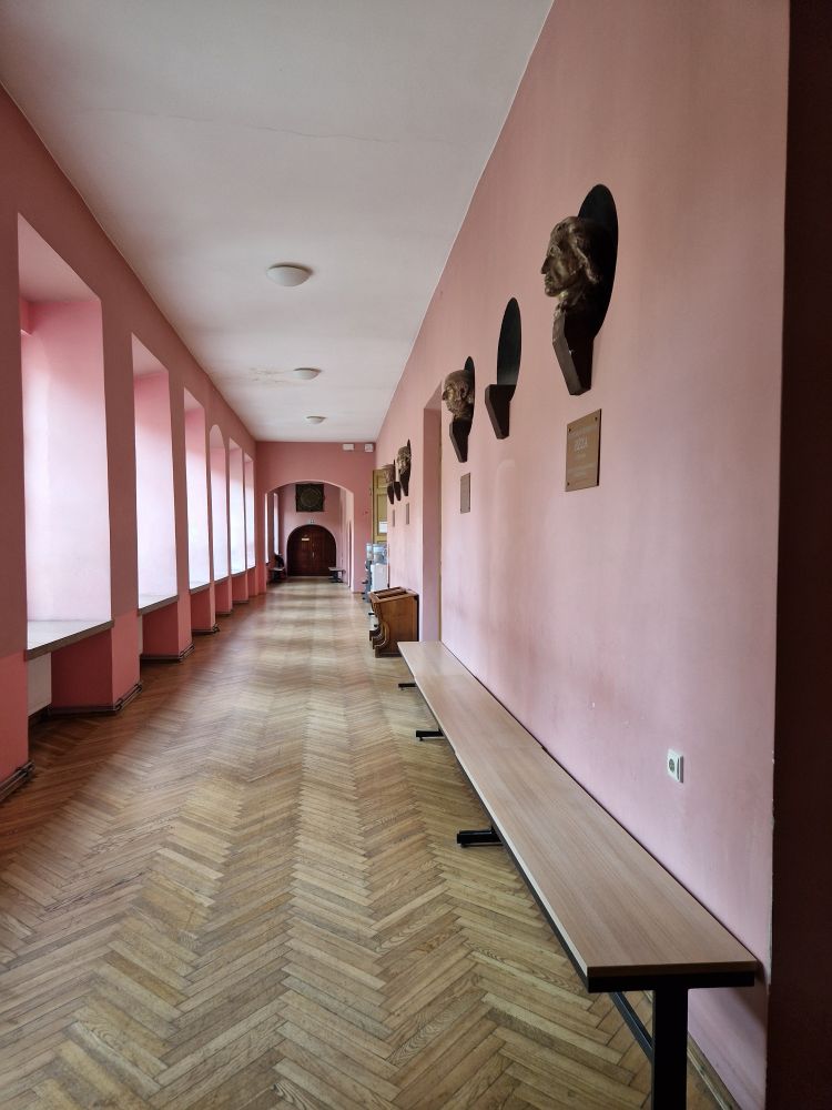 Pink hallway with benches and busts of people